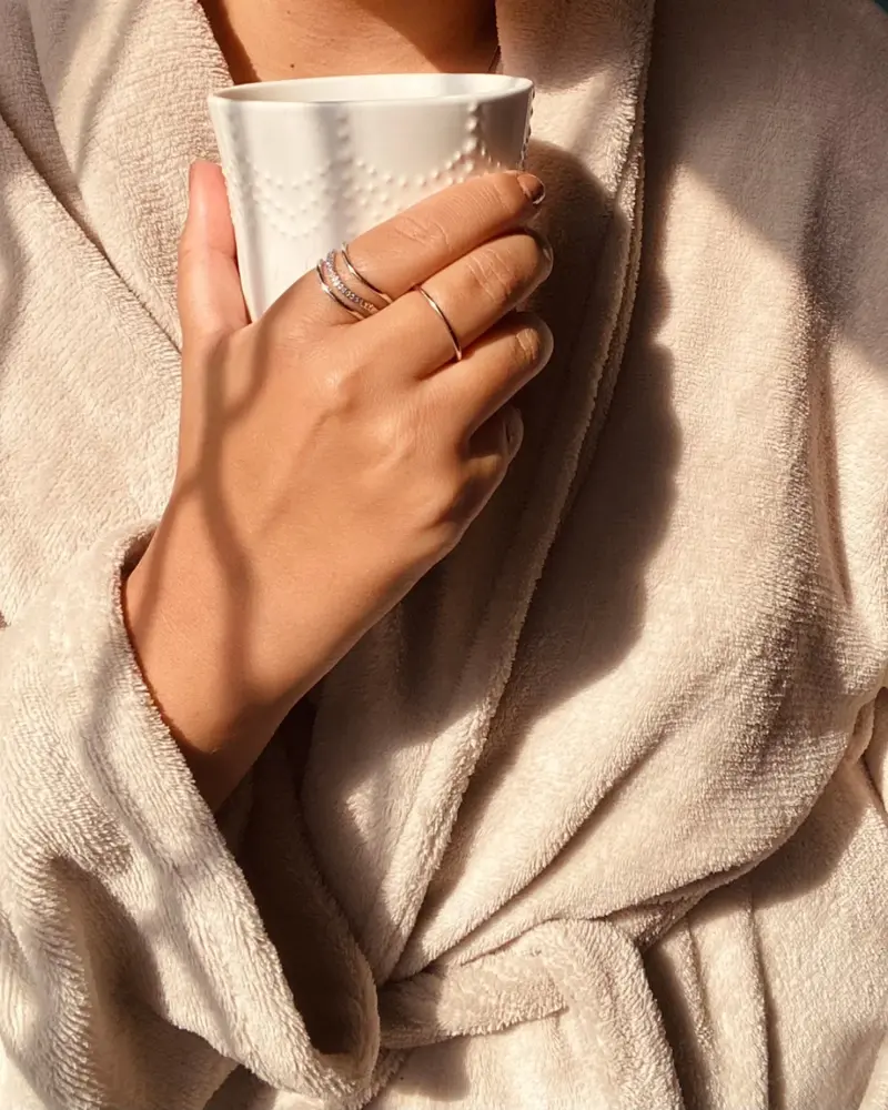 Person wearing a bathrobe holding a warm drink during a quiet self-care moment